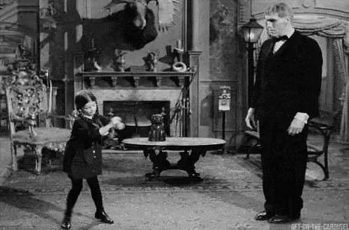 A black-and-white sequence from a classic film shows a young girl in a dark coat and boots energetically dancing or twirling…