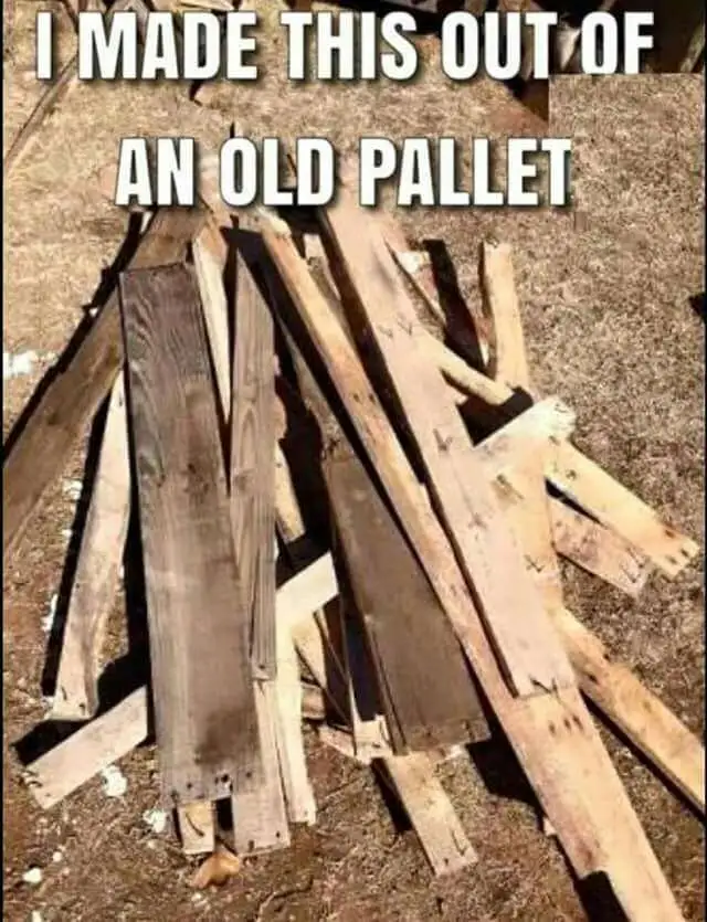 A pile of weathered, splintered wooden planks, likely from a disassembled pallet, is arranged haphazardly on dry dirt…