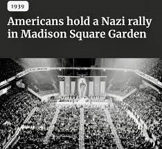 A black and white photo shows a large crowd in a stadium, with a stage at the far end. The image is overlaid with the text…