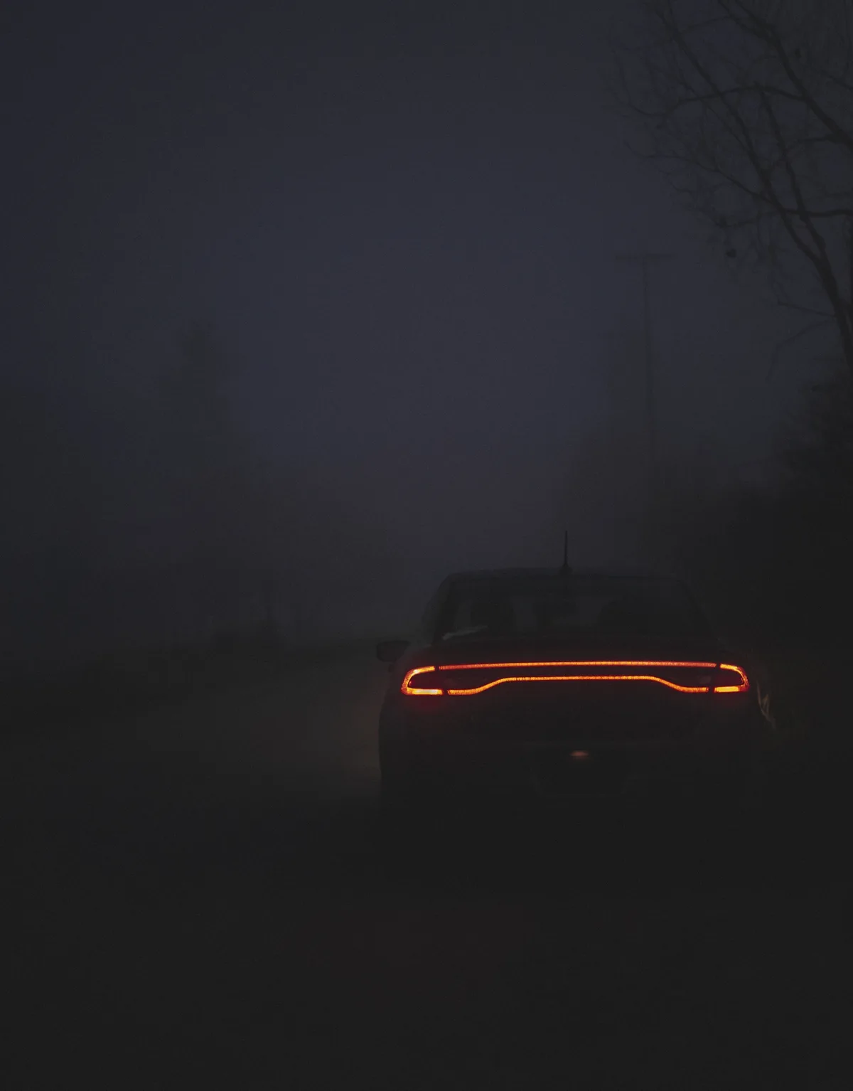 A car's glowing orange taillights are the only visible feature in a dark, foggy scene, with the overlaid text reading 'i'm…