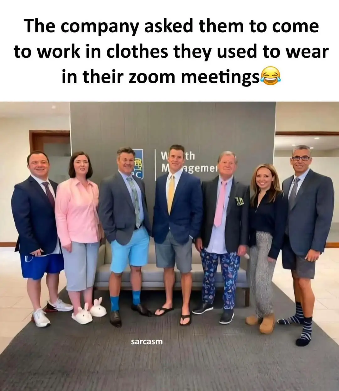 Seven people pose for a corporate photo in a lobby, but their outfits are absurdly casual: one wears bunny slippers, another…