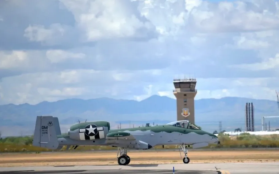 A military aircraft, resembling a fighter jet with green and gray camouflage and a star insignia, is parked on an airport…