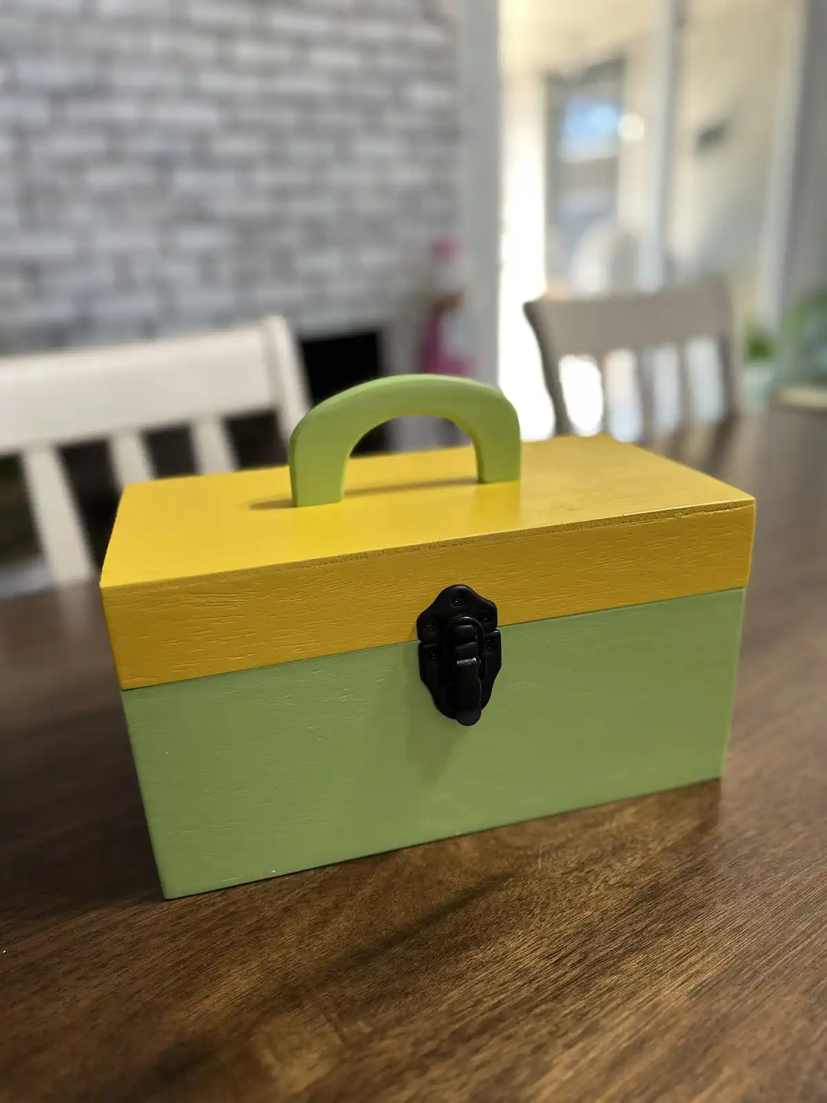 A yellow and green painted wooden box with a black latch and handle sits on a wooden table. The overlaid text reads 'i'm not…