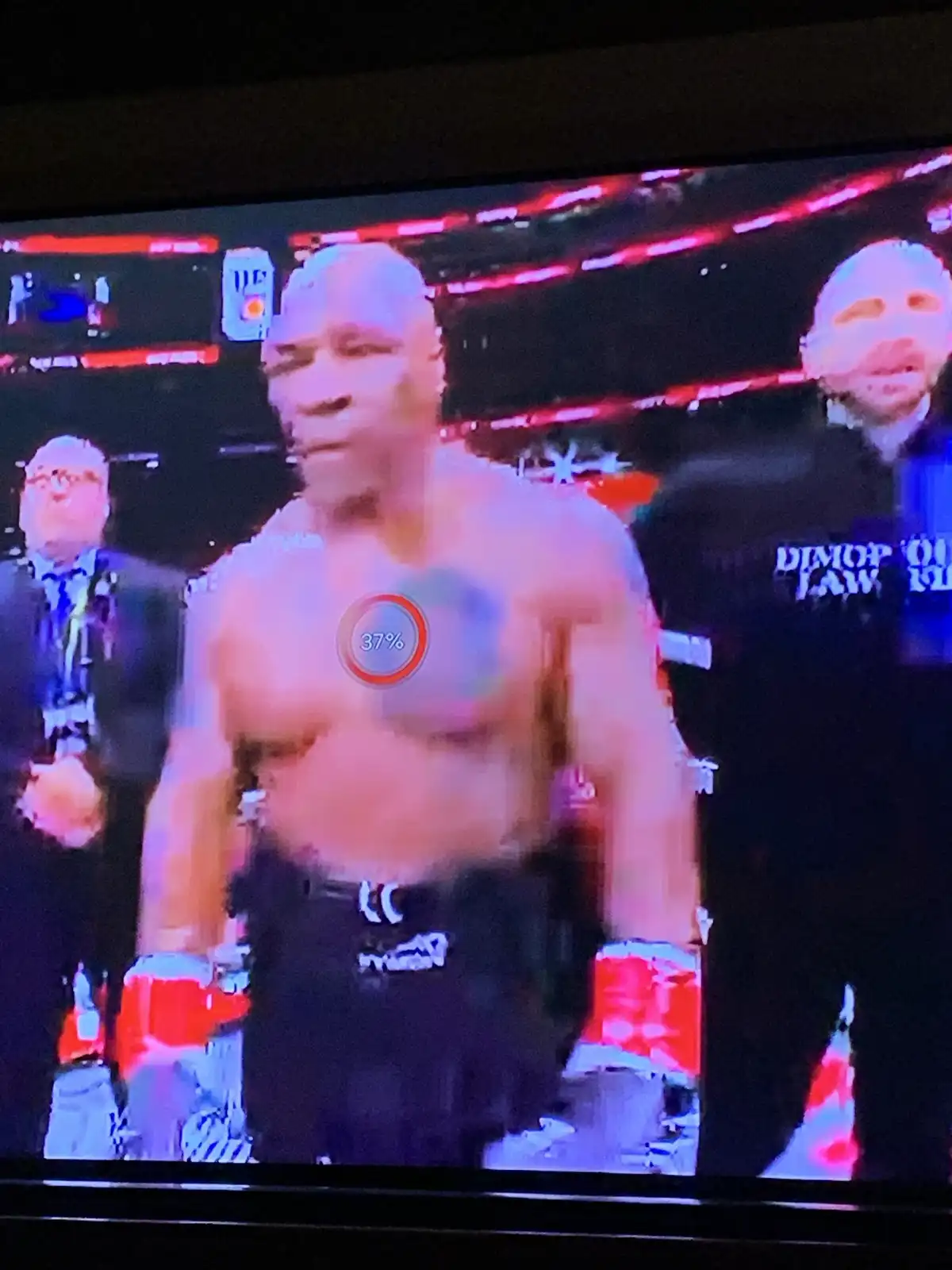 A shirtless boxer stands in a ring with a digital overlay showing '37%' on his chest, humorously implying his remaining…