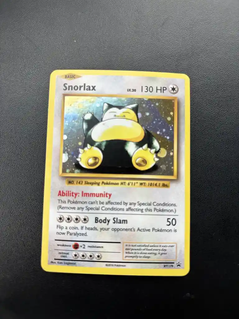 A Pokémon trading card featuring Snorlax, a large, sleeping, black-and-yellow creature, with text describing its ability…