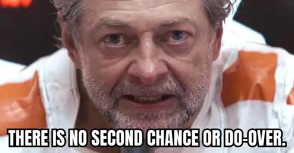 A close-up of a man with gray hair and a beard, wearing a white and orange striped shirt, looking intensely at the camera…