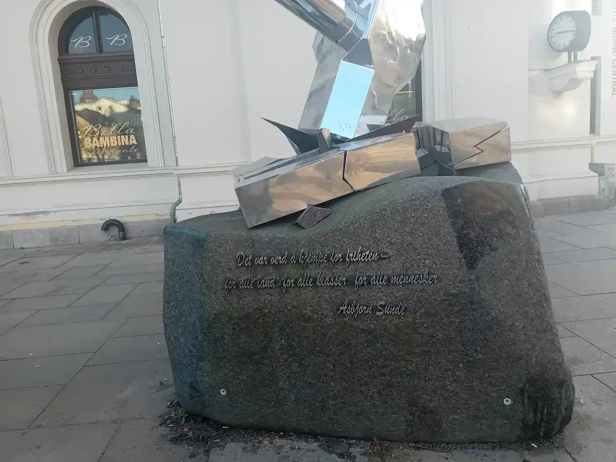 A large, dark granite monument with engraved text in Norwegian reads 'Det var verd å kjempe for friheten - for alle land…