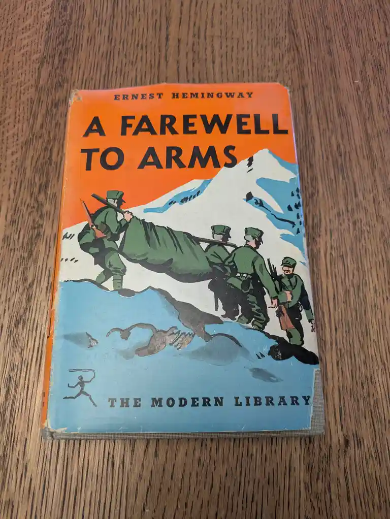 A vintage paperback book cover of Ernest Hemingway's 'A Farewell to Arms' from The Modern Library, featuring an illustration…