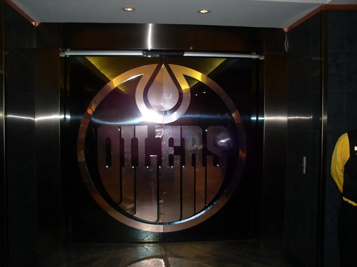 A close-up of a large, metallic elevator door featuring the Edmonton Oilers NHL hockey team logo, which includes a stylized…
