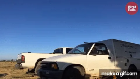 A white pickup truck with a cargo box is shown in a desert-like setting under a clear blue sky. The truck is parked next to…