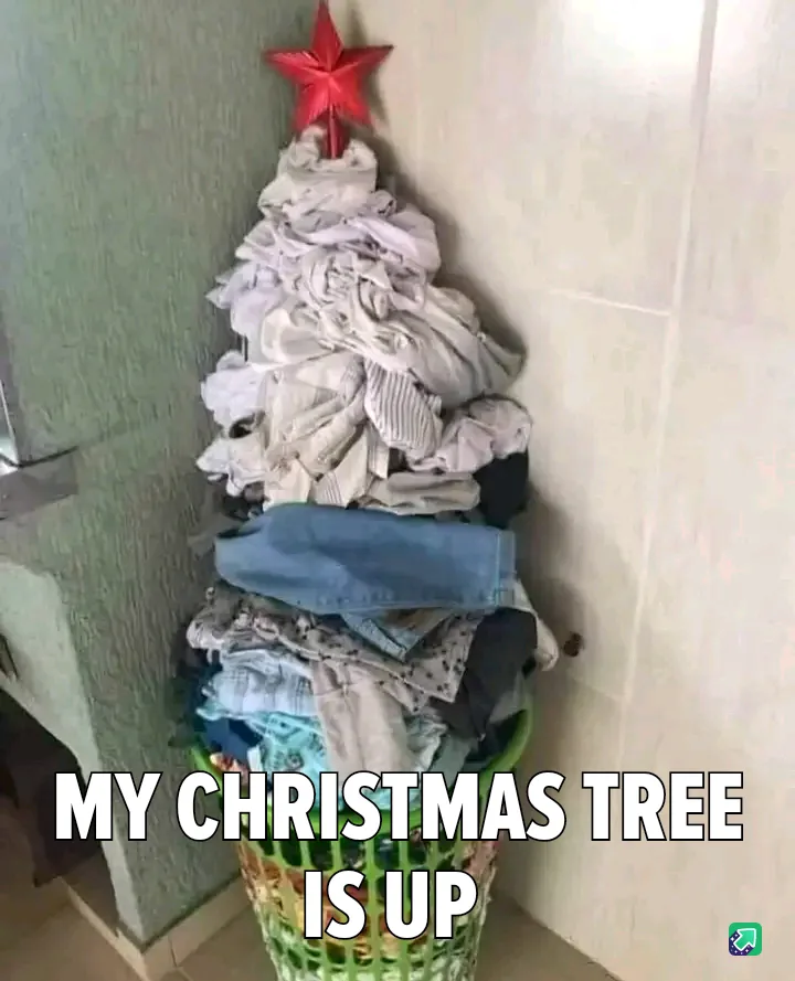 A laundry basket overflowing with clothes is shaped into a Christmas tree, topped with a red star, with the text 'MY…