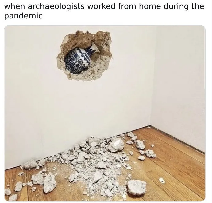 A blue and white patterned ceramic vase is partially embedded in a hole in a white wall, with chunks of drywall debris…
