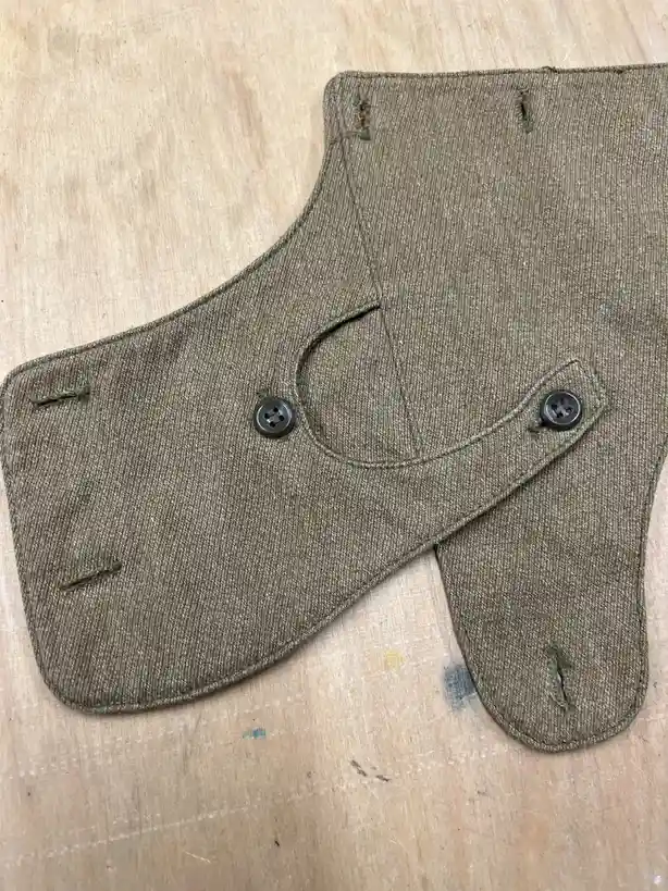A close-up photo shows a brown, textured fabric mask shaped like a human face, complete with two black buttons serving as…