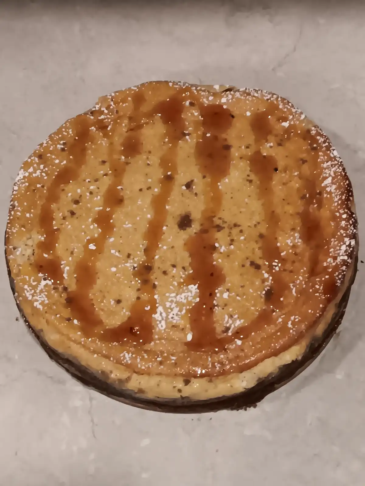 A round cake with a caramel drizzle and powdered sugar sits on a marble surface. The overlaid text reads 'i'm not a fan of…