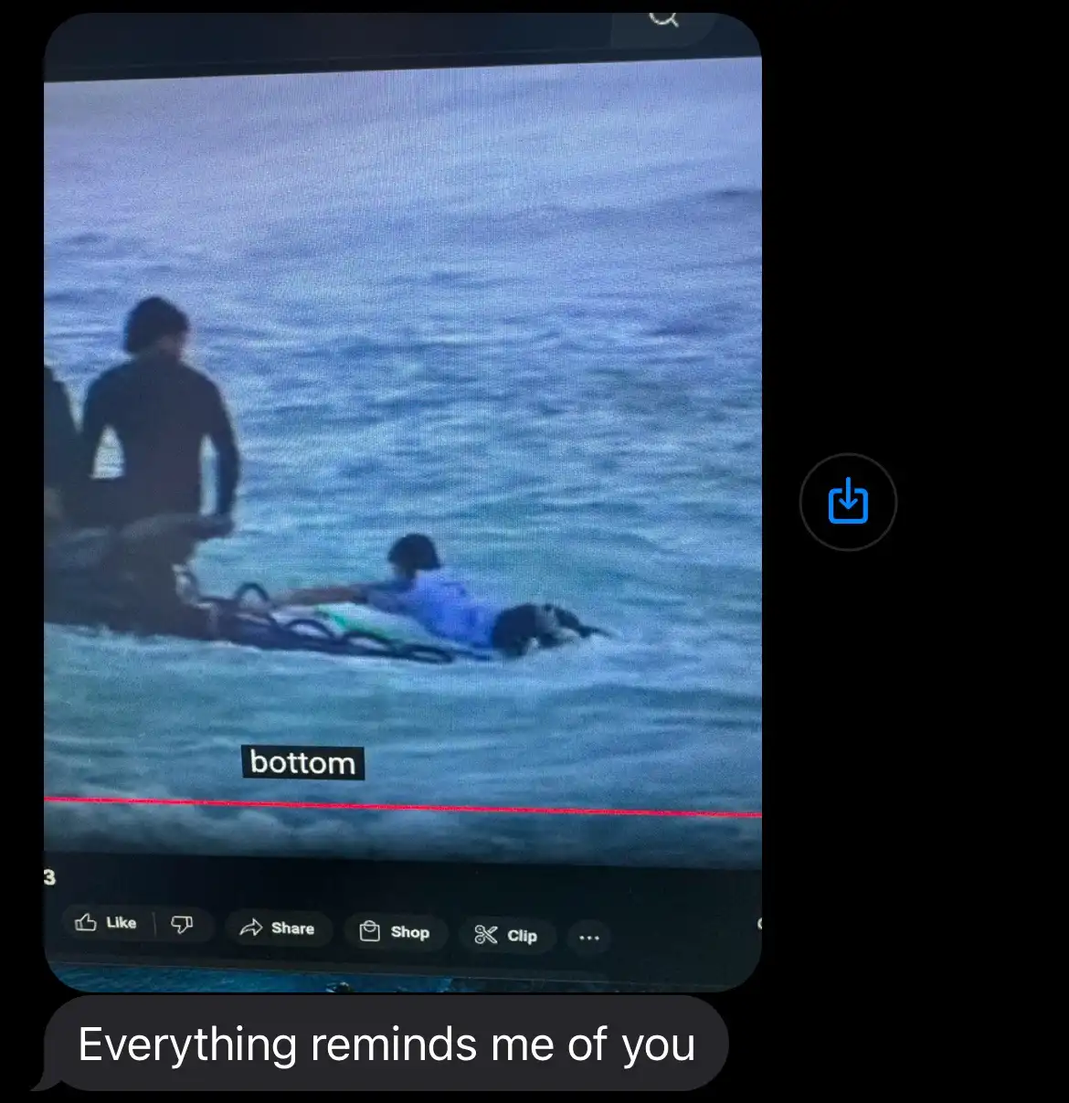 A screenshot of a social media video shows two people in the ocean; one is standing while the other is lying on a surfboard…