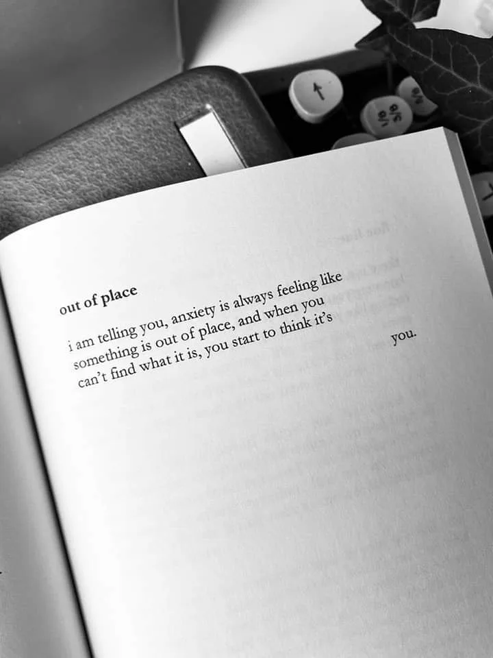 A black-and-white photo shows an open book with the title 'out of place' and a short poem about anxiety feeling like…