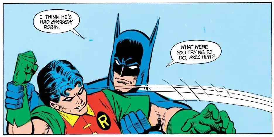 Batman is holding Robin by the shoulders in a comic panel, looking sternly at him. Robin, wearing his red and green costume…