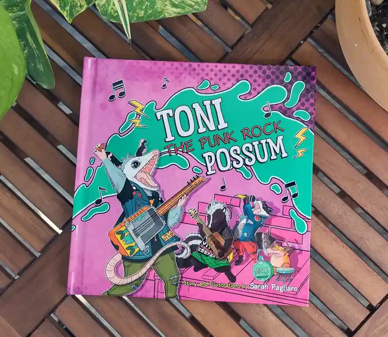 A children's book titled 'TONI THE PUNK ROCK POSSUM' by Sarah Pagliaro, featuring a cartoon possum playing guitar with a…