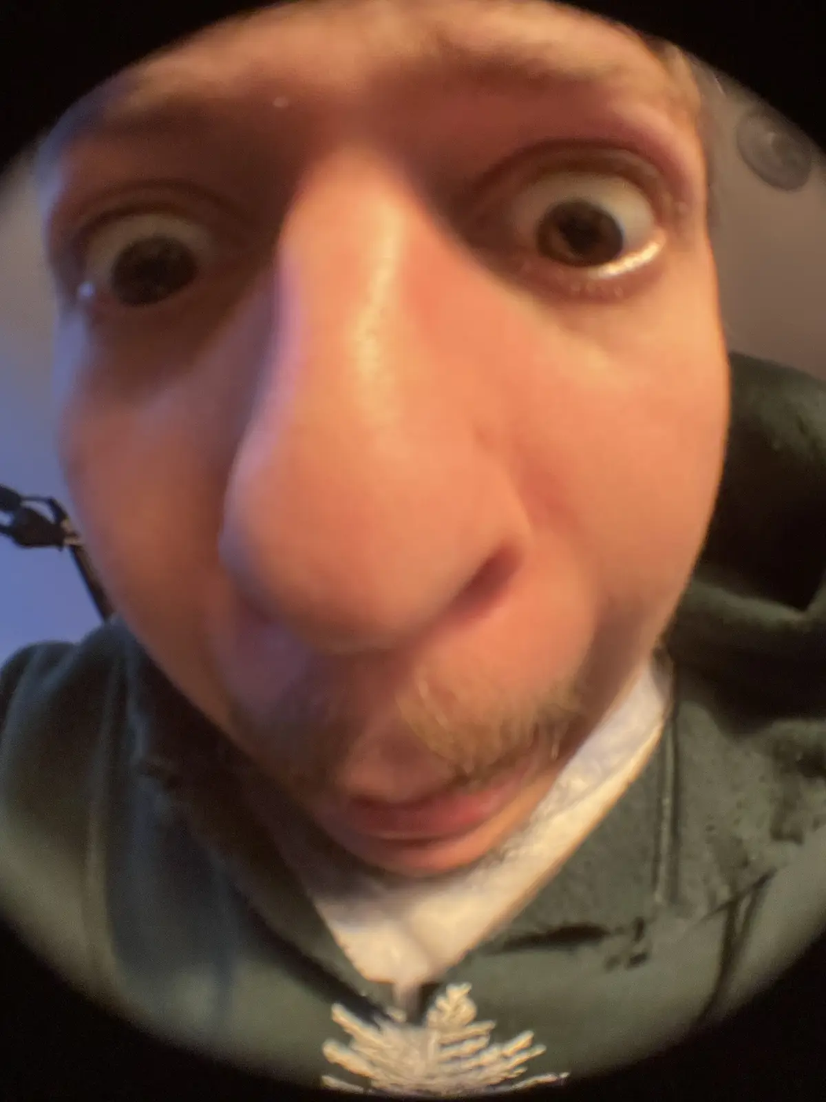 A close-up, fisheye-lens selfie shows a person with an exaggeratedly distorted face, featuring bulging eyes and a magnified…