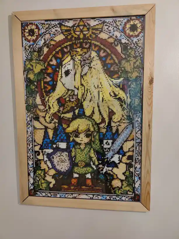 a framed artwork made of colorful perler beads depicts a scene from The Legend of Zelda, featuring Link and Zelda in a…