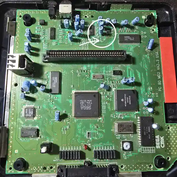 A close-up photo of a green Sega PC BD MD2 VA2.3 USA arcade circuit board, highlighting a small black integrated circuit…