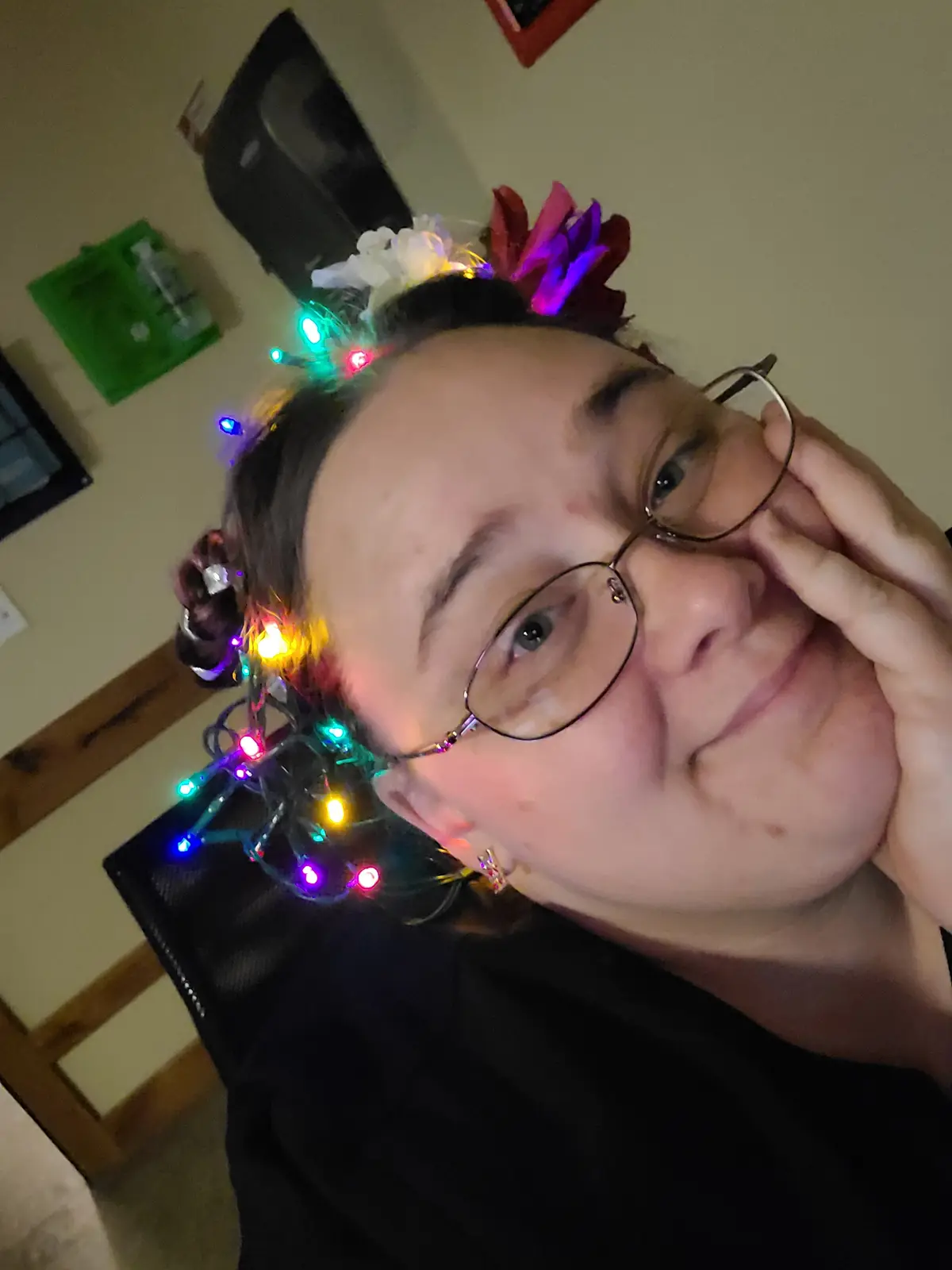 A person with glasses and a slight smile is shown from a tilted angle, wearing a headband decorated with colorful string…