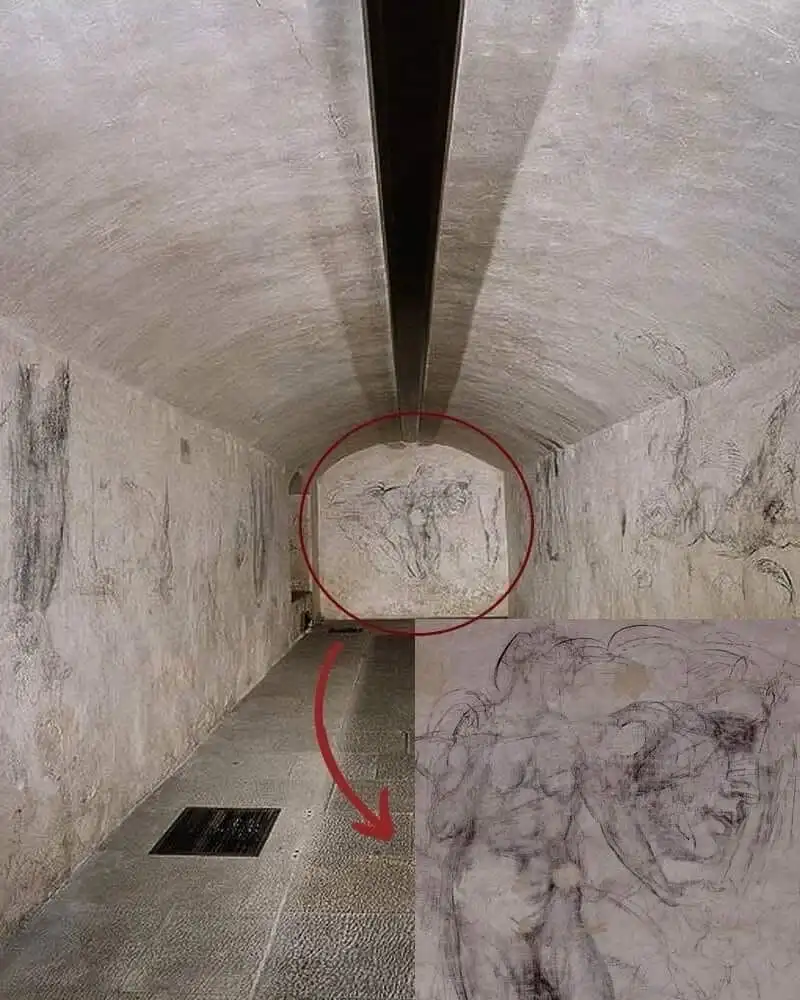 A narrow concrete tunnel with rough walls and a vaulted ceiling, featuring faint pencil sketches of human figures. A red…