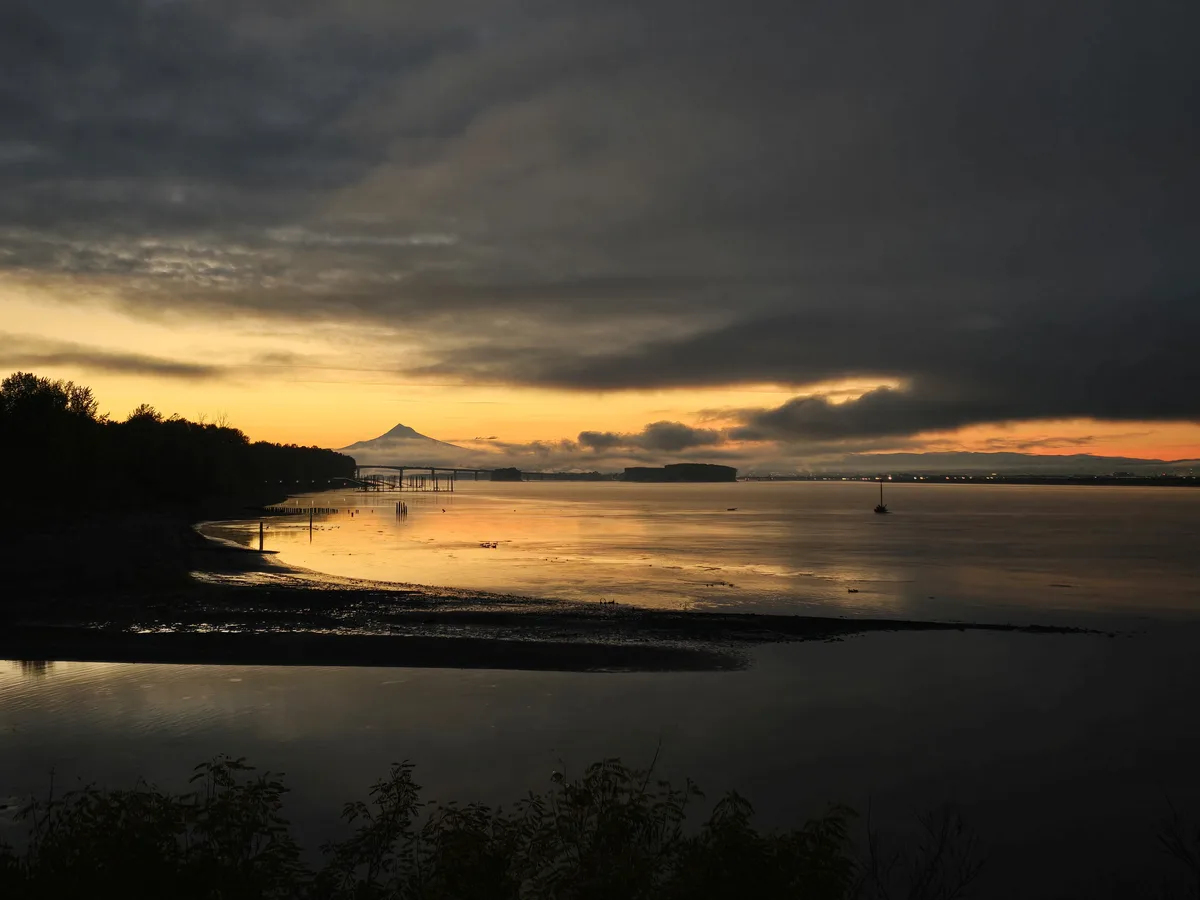 A serene sunset over a body of water with a distant mountain and bridge, overlaid with the text 'i'm not crying, you're…