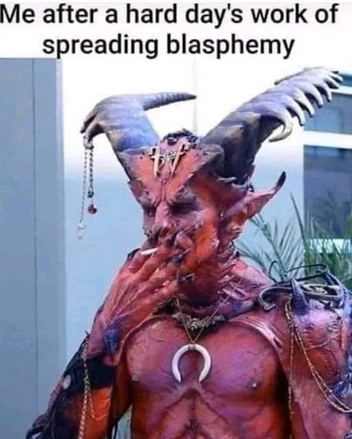 A person in elaborate demonic costume with horns, claws, and a crescent moon necklace is seen smoking a cigarette. The…