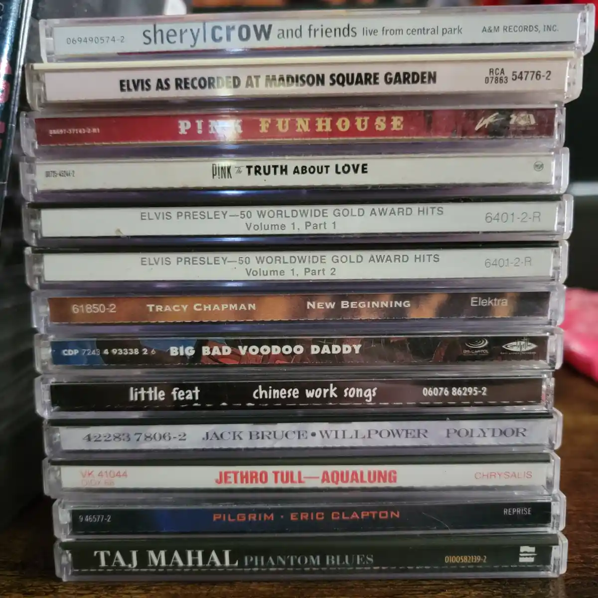 A stack of cassette tapes with visible album titles like 'Sheryl Crow and Friends', 'Elvis at Madison Square Garden', 'Pink…