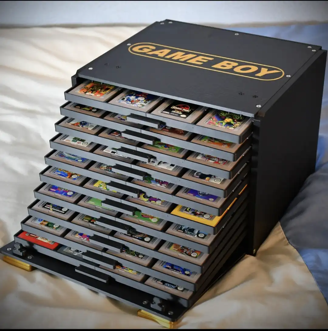 A black, custom-built, multi-drawer organizer shaped like a Game Boy, with each drawer holding a Game Boy cartridge. The top…