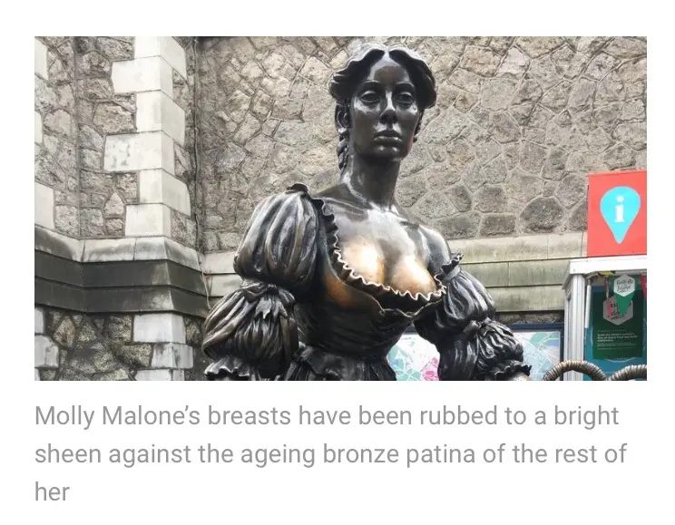 A bronze statue of Molly Malone, a famous Irish folk song character, shows her bust with a noticeably shiny, polished…