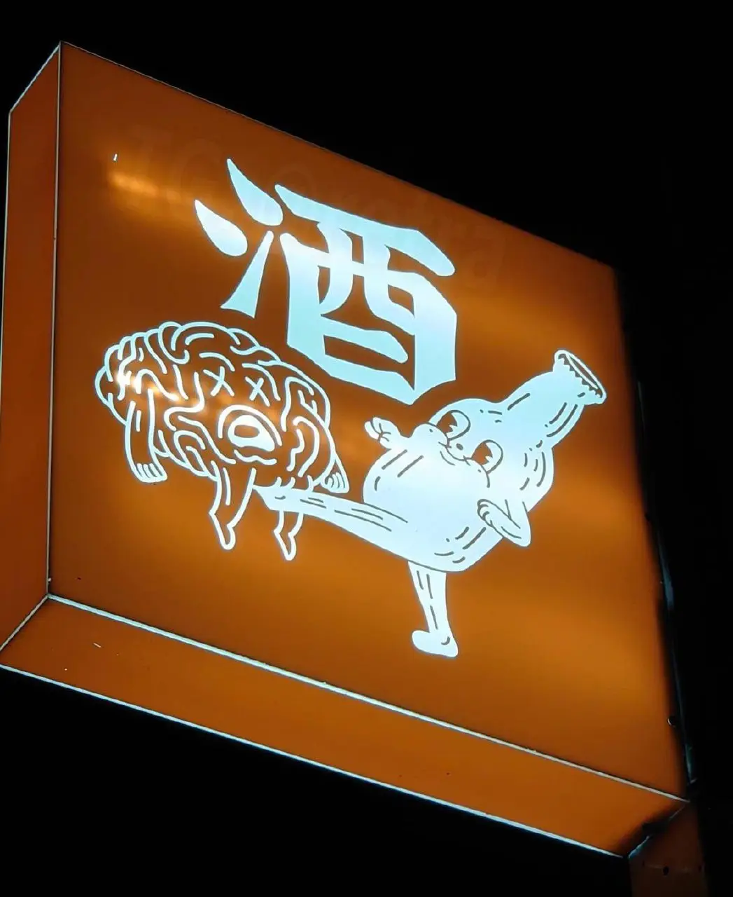 An illuminated orange sign at night displays a large white Chinese character '酒' (jiǔ, meaning alcohol) above a cartoonish…