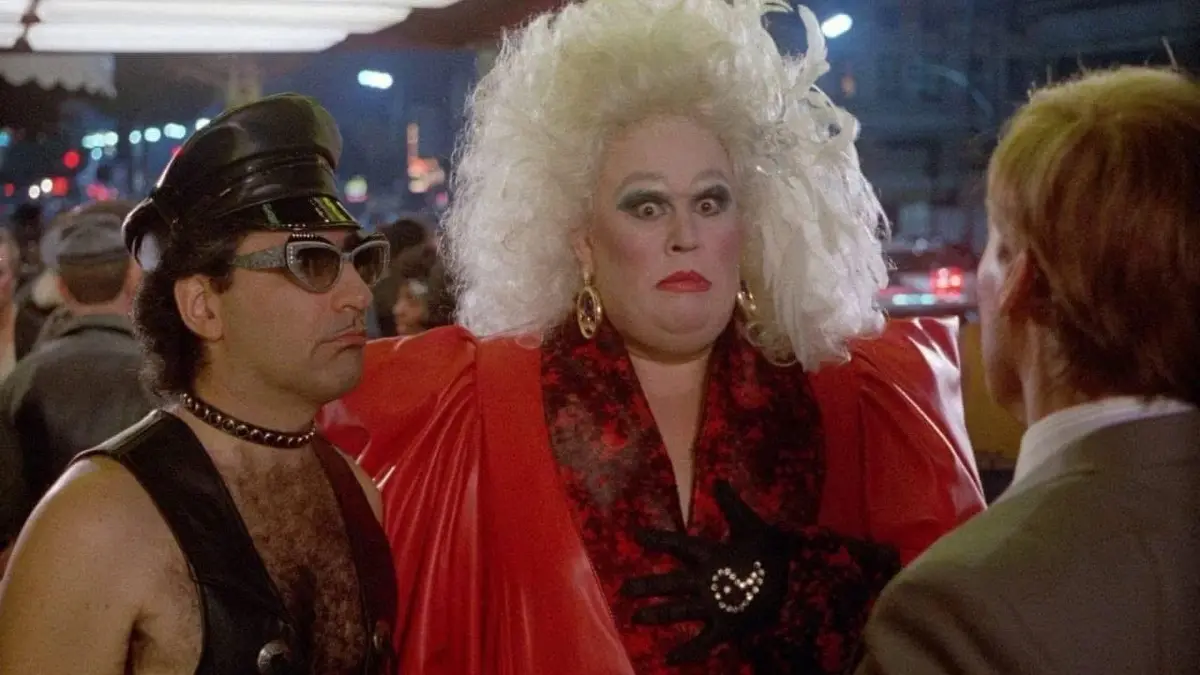 a still from the movie 'The Rocky Horror Picture Show' featuring a person in a large white wig and red outfit with a shocked…