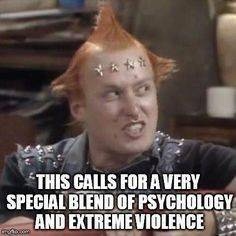 A man with spiky red hair and star-shaped hairpins looks intensely at the viewer, wearing a studded black shirt. The…
