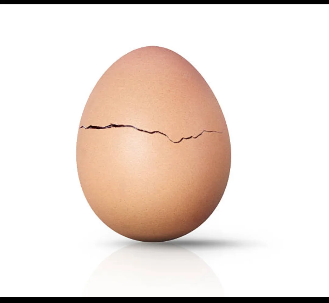 A single brown egg with a prominent horizontal crack across its shell, set against a plain white background with a subtle…