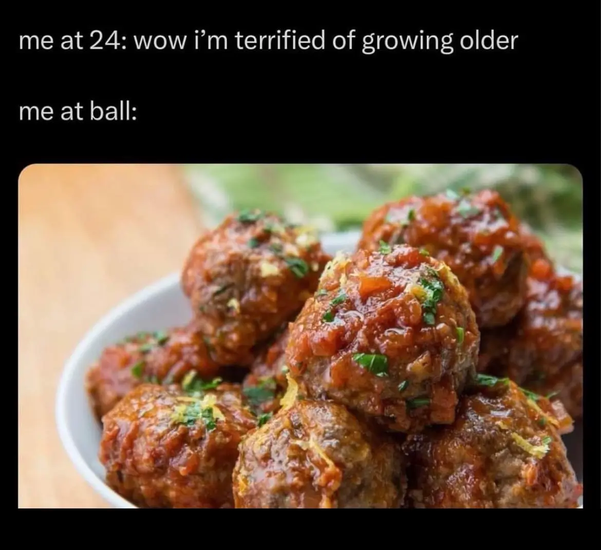 A close-up photo of meatballs in a red sauce, garnished with chopped green herbs and lemon zest, piled in a white bowl. The…