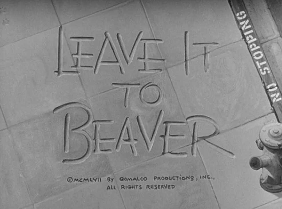 A black-and-white image shows the title 'LEAVE IT TO BEAVER' carved into sidewalk tiles, with a fire hydrant and a 'NO…