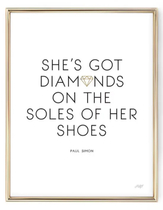 A framed poster with black serif text on a white background reads 'SHE'S GOT DIAMONDS ON THE SOLES OF HER SHOES', with a…