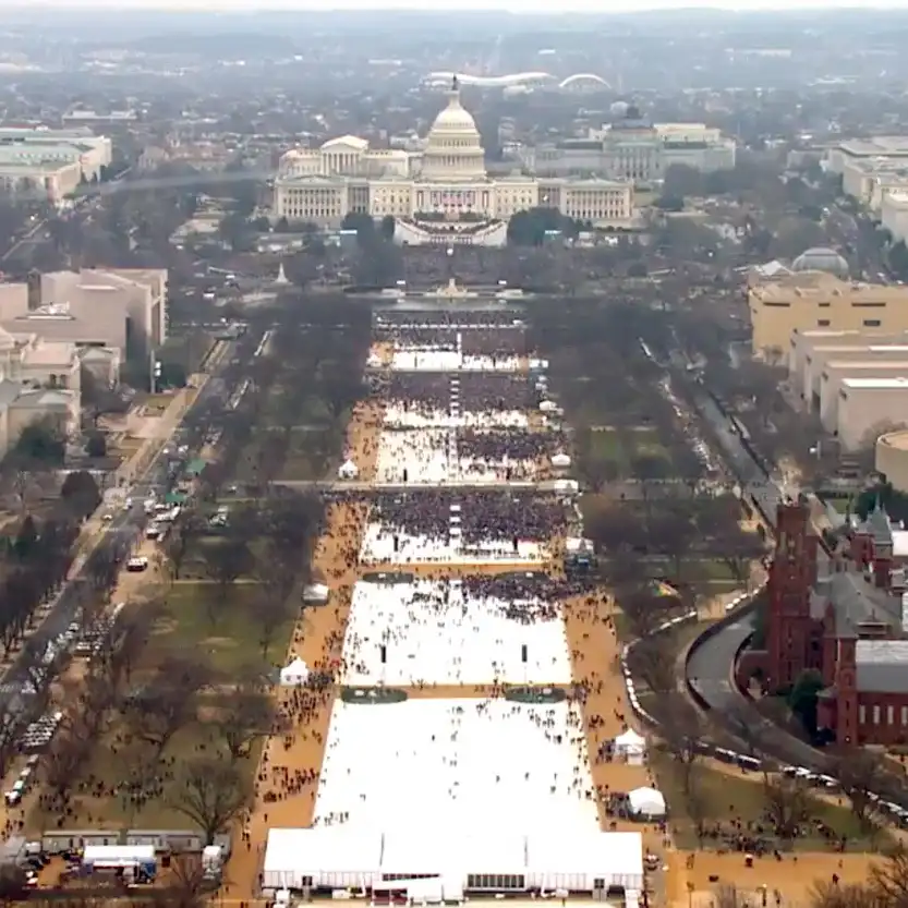 an aerial view shows the u.s. capitol building with a large crowd of people gathered in the national mall, forming a dense…
