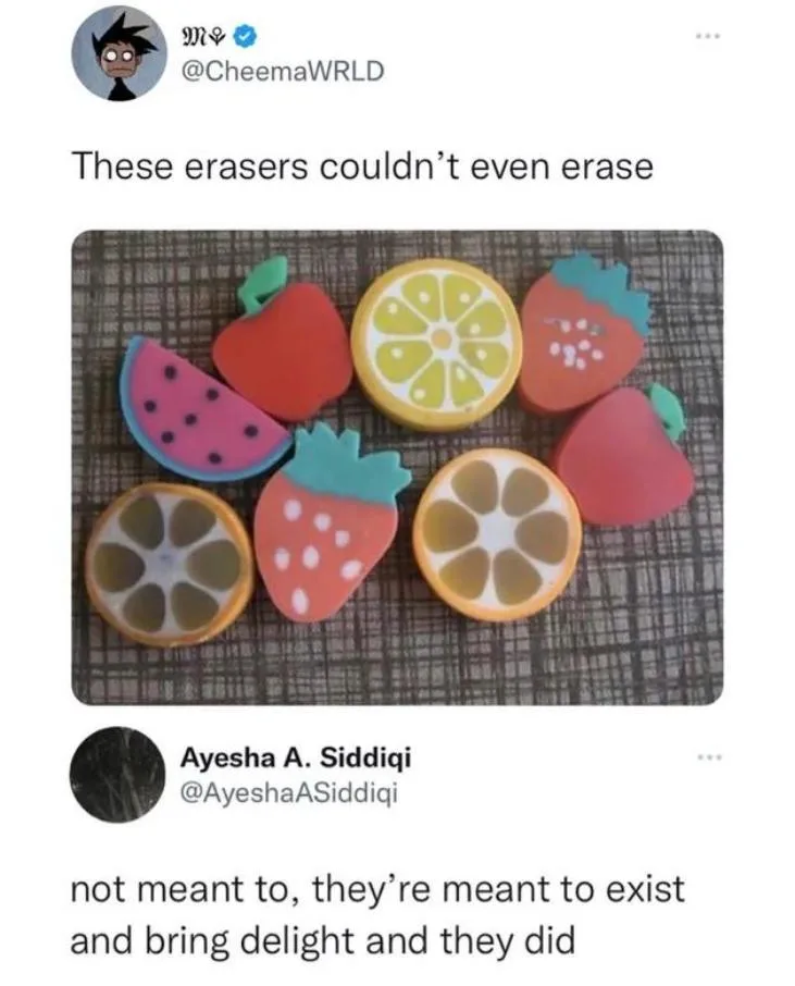 A photo shows seven colorful, fruit-shaped erasers (watermelon, apple, lemon, strawberry) arranged on a textured surface…