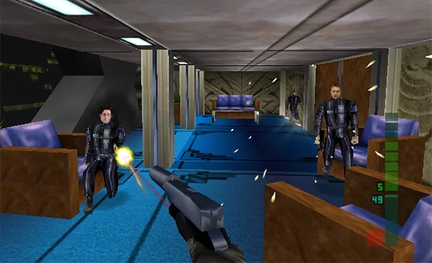 A first-person shooter game screenshot shows the player aiming a gun at a man in a black suit sitting in a chair. Another…