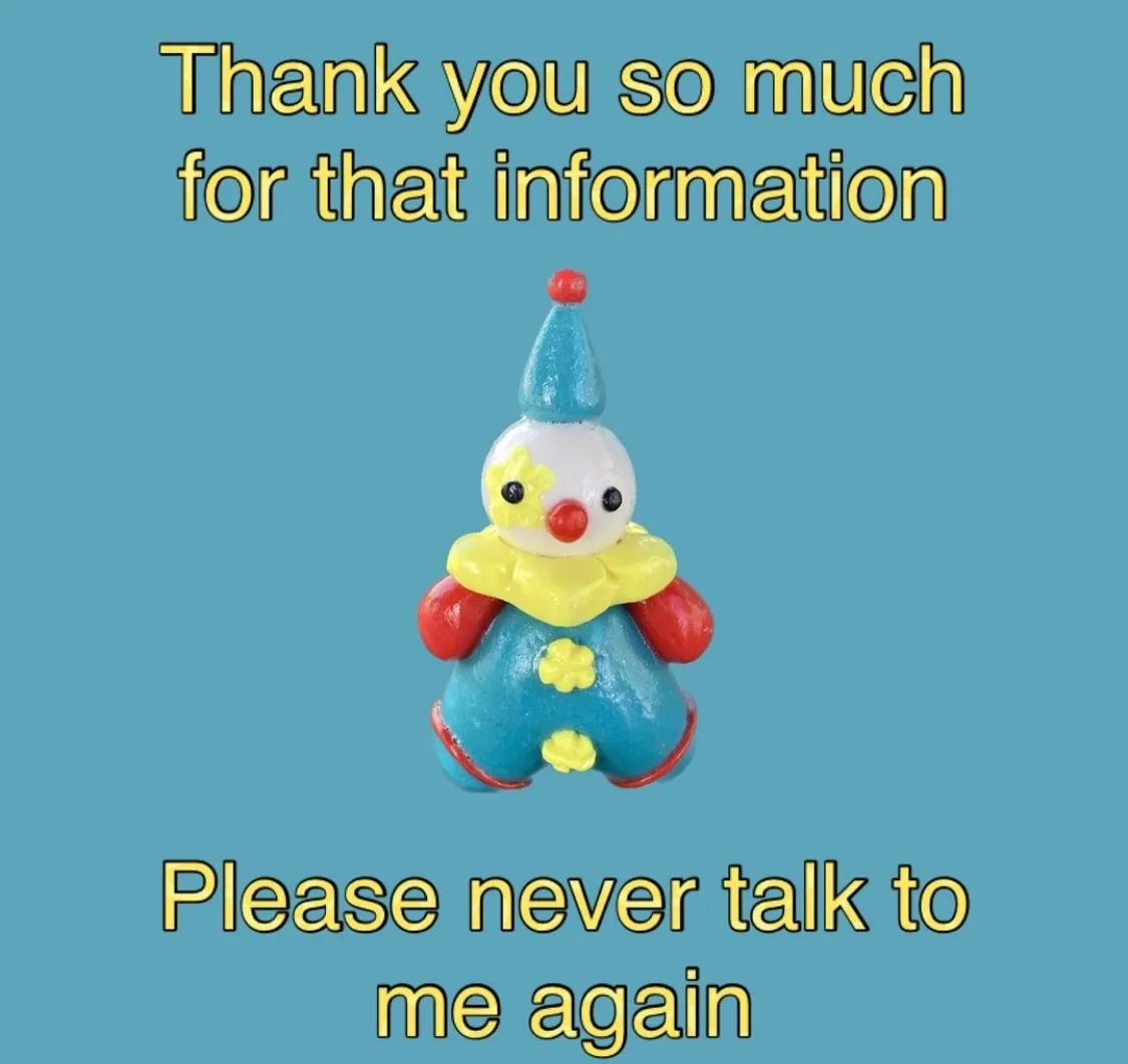 A small, colorful plastic clown figurine with a blue hat, red nose, and yellow collar is centered on a solid teal…