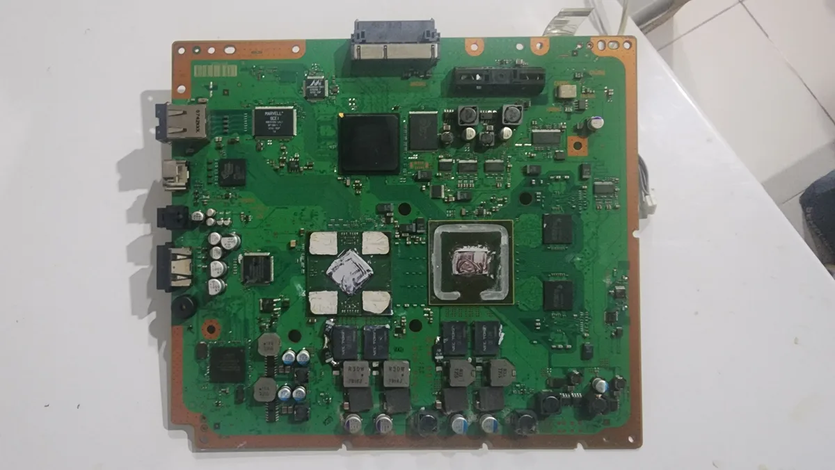 A close-up photo of a green circuit board with various electronic components, including chips, capacitors, and connectors…