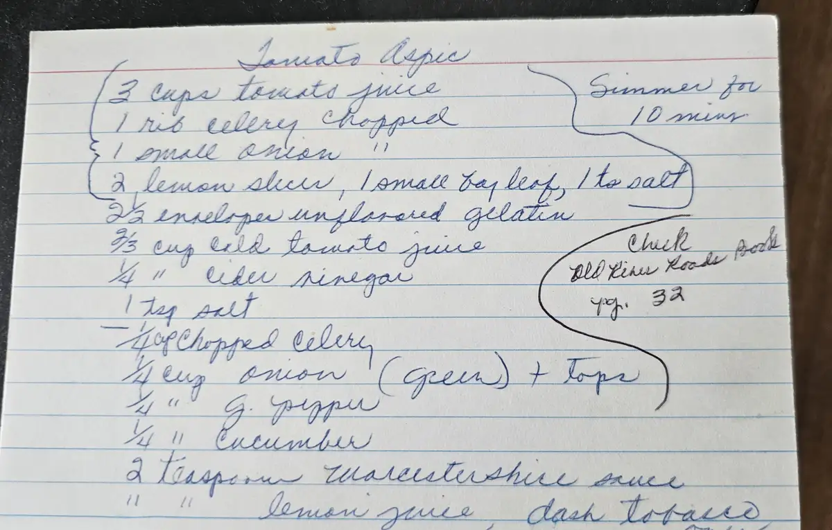A handwritten recipe for 'Tomato Aspic' on lined paper lists ingredients like tomato juice, celery, onion, gelatin, vinegar…