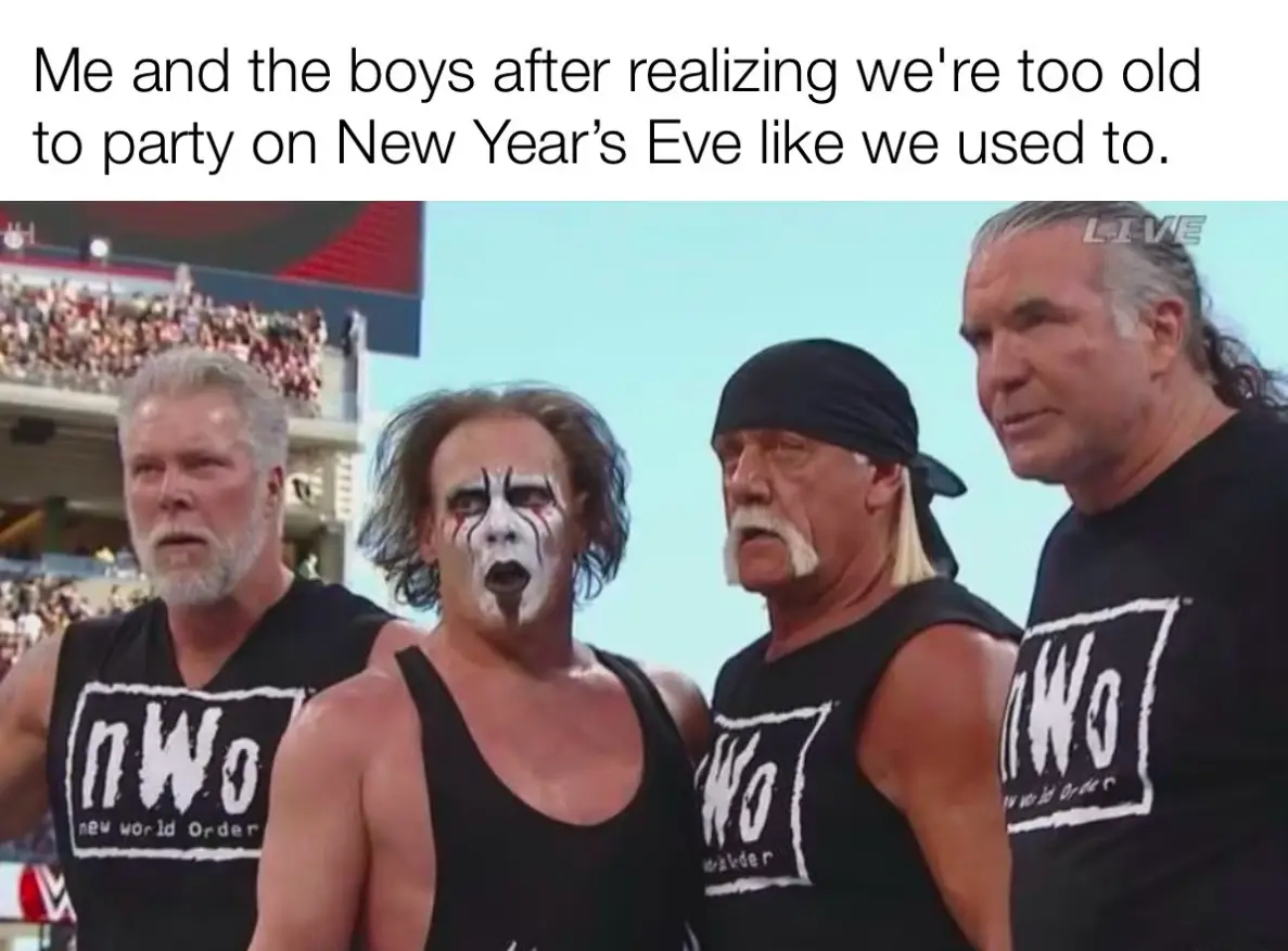 Four men in black tank tops with 'nWo' logos stand in a wrestling arena, looking solemn and resigned. The man second from…