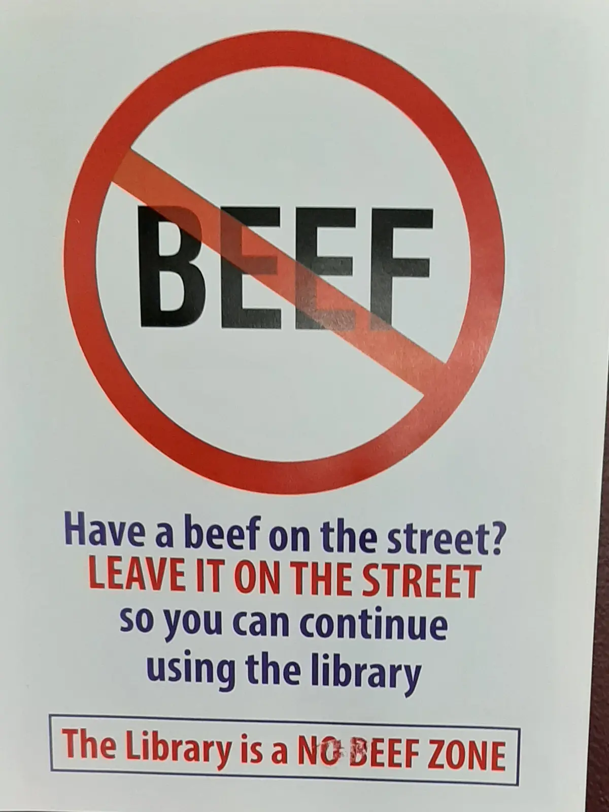 A library sign features a red prohibition symbol over the word 'BEEF'. Below, text advises patrons to 'Leave it on the…