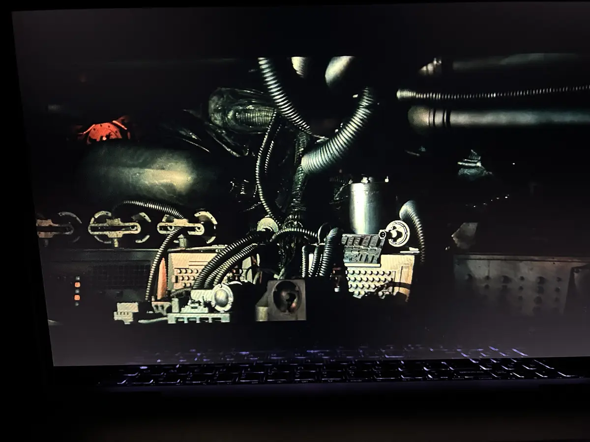 A laptop screen displays a dark, industrial scene with pipes, valves, and machinery, overlaid with the text 'i'm not a fan…