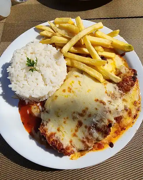 A plate of chicken parmigiana topped with melted cheese, served with golden french fries and a scoop of white rice garnished…