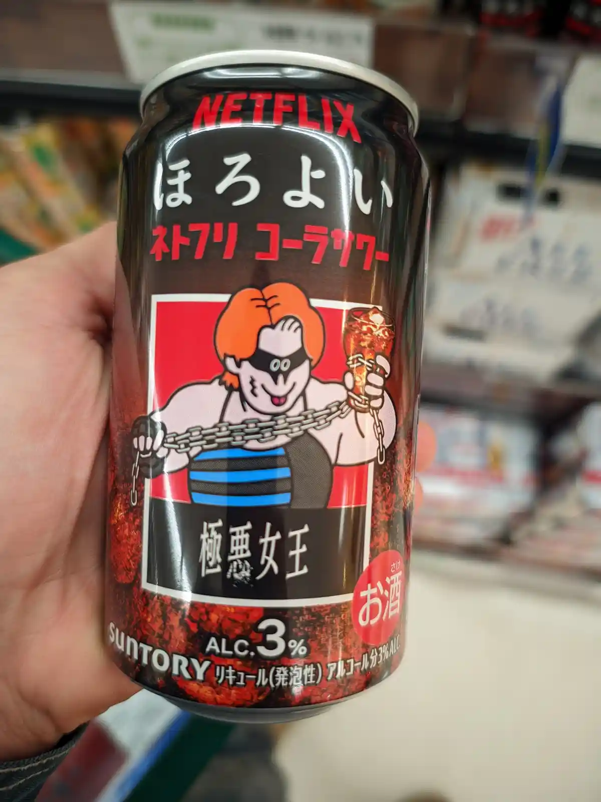 A hand holds a black can of Suntory's 'Horoyoi Netflix' alcoholic beverage, featuring a cartoon character with orange hair…